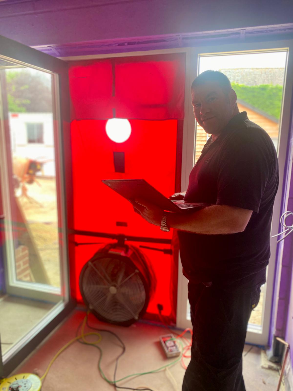 Technician conducting blower door airtightness test to verify Passive Purple vapour control performance in energy-efficient construction