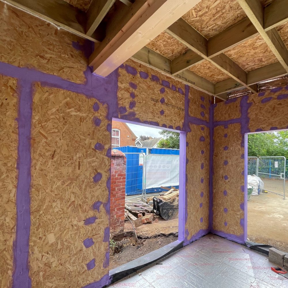 Close-up of Passive Purple Brush sealing OSB board joints to prevent air leakage and improve energy efficiency.